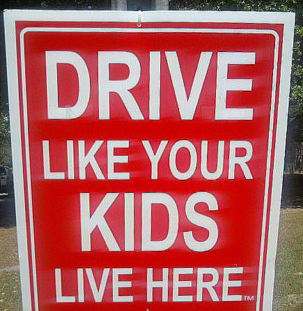 Road sign that says "Drive Like Your Kids Live Here: